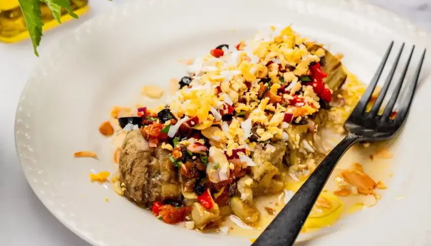 Deliciosa ensalada de berenjenas asadas con huevo picado, aceitunas negras, pimientos y almendras.