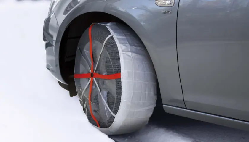 Neumático de coche con cadenas de nieve puestas, ideal para saber donde se colocan las cadenas de nieve en condiciones de hielo.