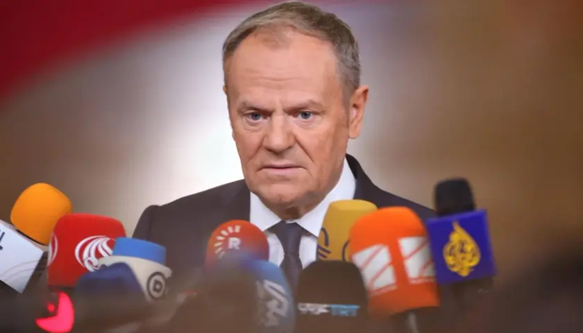 Donald Tusk w Ustroniu, otoczony przez mikrofony mediów, gotów do udzielenia wywiadu.