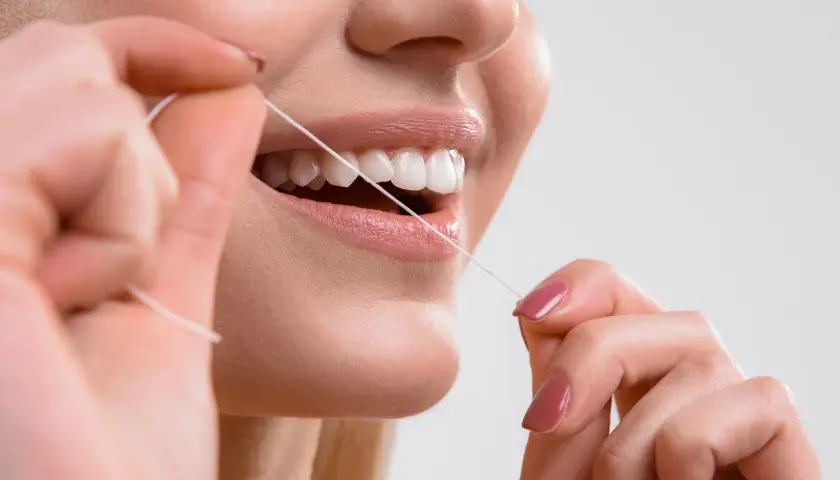 Primo piano di una donna che usa il filo interdentale per pulire i denti. Impara scovolino denti come si usa per un sorriso smagliante.