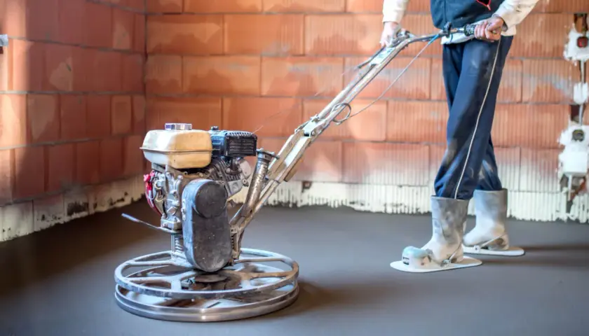 Operaio usa una levigatrice per cemento per lisciare il pavimento di una casa in costruzione.