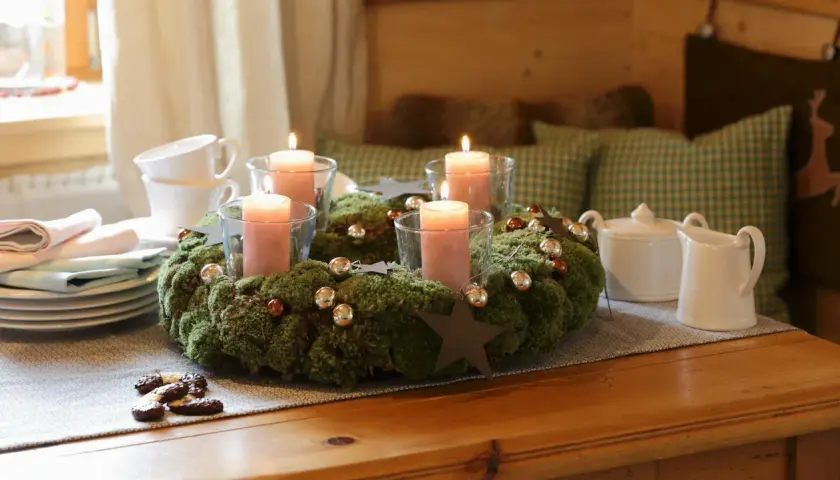 Ein Adventskranz aus Moos mit vier rosa Kerzen, Kugeln und Sternen. Tolle Adventsdeko Ideen für ein gemütliches Zuhause.