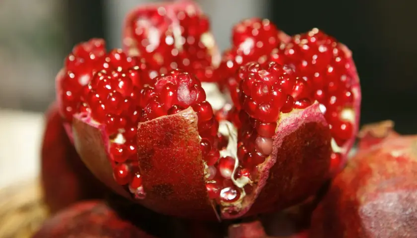 Ein aufgeschnittener Granatapfel mit saftigen roten Kernen. Die **Granatapfelextrakt Wirkung** ist bekannt für ihre antioxidativen Eigenschaften.