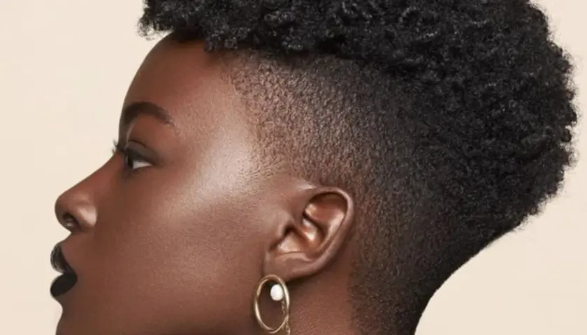 Perfil de mujer con cabello rizado y un moderno taper fade bajo.