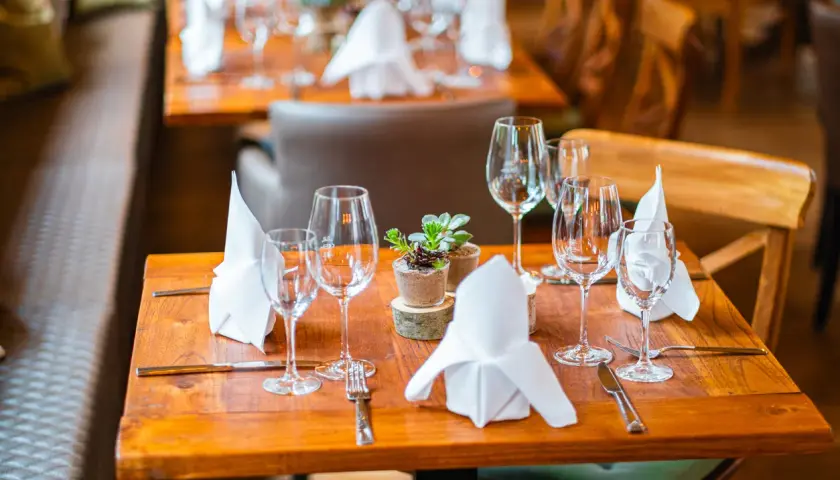 Ein gedeckter Tisch mit Sektgläsern, Servietten und einer kleinen Pflanze. Die Gläser sind bereit für den Anlass, aber wie viel passt in ein Sektglas?