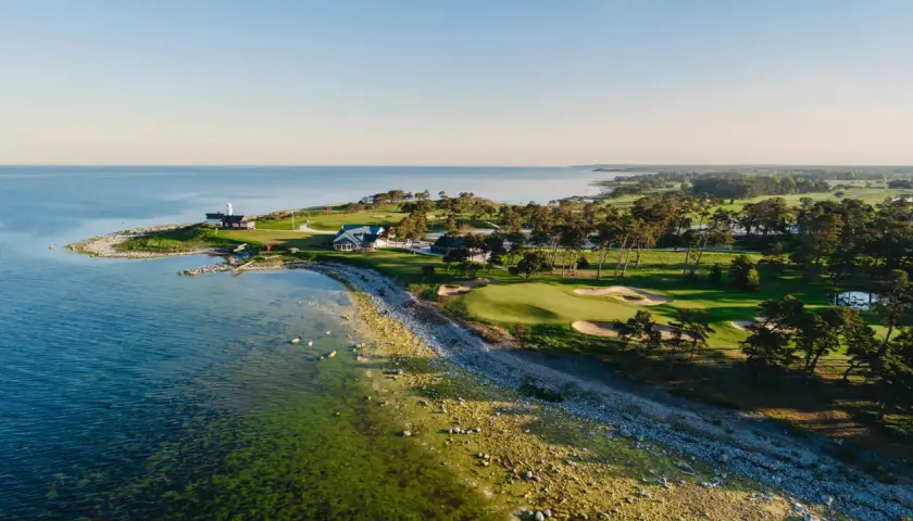 Vacker kustlinje med fina golfbanor Sverige. Grönskande fairways, sandbunkrar och en fyr vid havet.