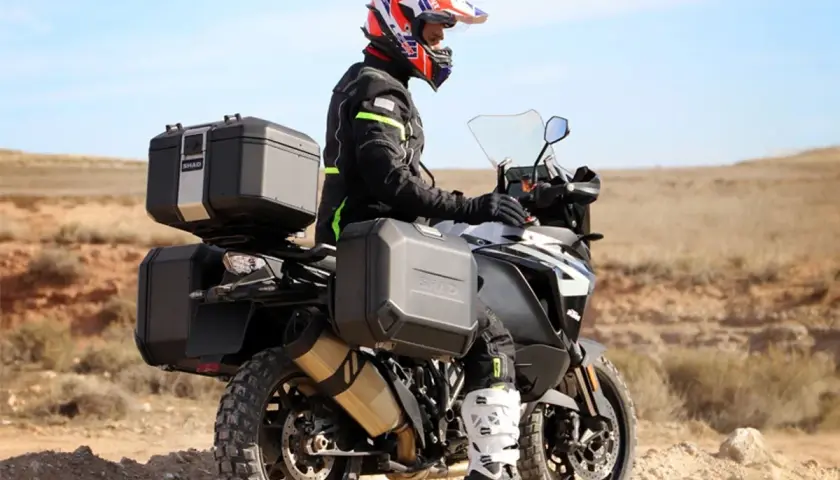 Motociclista con casco y equipo de aventura, listo para explorar. Como se llama el maletero de la moto, es un accesorio esencial para llevar todo lo necesario.