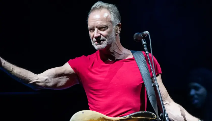 Sting w czerwonej koszulce, z gitarą i mikrofonem, jakby śpiewał o swoich dzieciach.