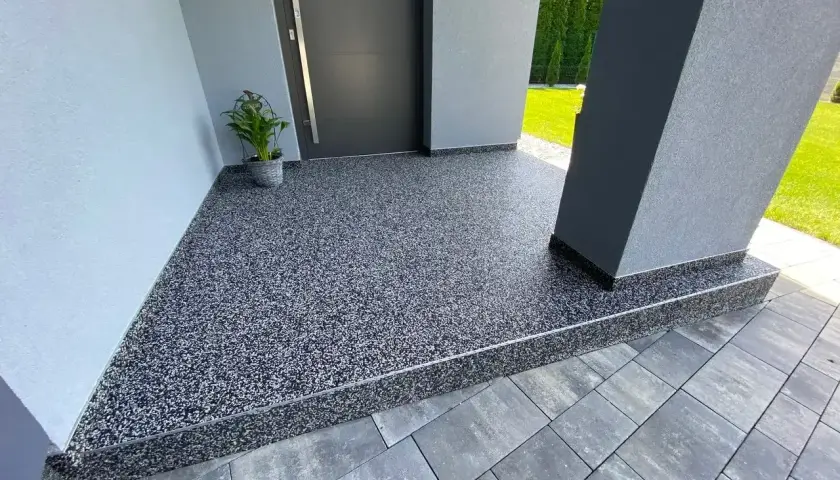 Nowoczesny kamienny dywan koszt 1m2 przy wejściu do domu. Elegancka, szara posadzka z drobnym kamyczkiem.