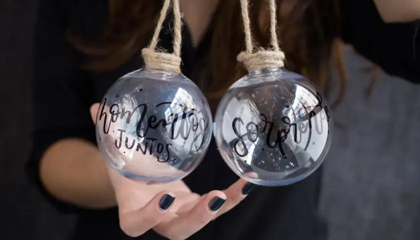 Dos bolas de navidad personalizadas con nombre, una dice "hogar" y la otra "juntos".