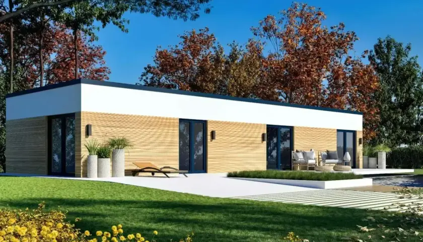Nowoczesny dom modułowy 100m2 cena pod klucz, z drewnianą elewacją, dużymi oknami i tarasem, otoczony zielenią i jesiennymi drzewami.