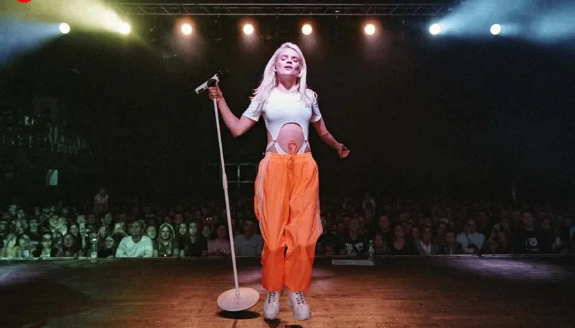 Margaret, dziękuję bardzo za wspaniały koncert! Wokalistka na scenie z mikrofonem, w pomarańczowych spodniach, przed rozentuzjazmowaną publicznością.