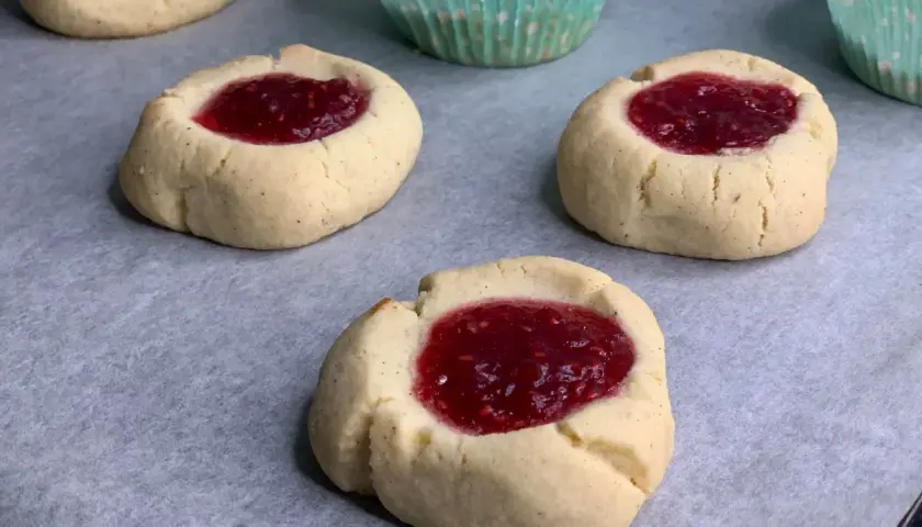 Nybakade glutenfria hallongrottor med sylt på bakplåtspapper. Perfekt fika!