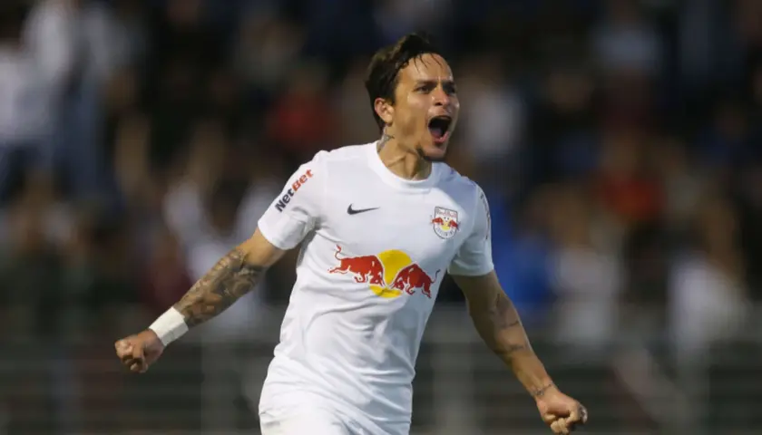 Piłkarz w białej koszulce z logo Red Bull świętuje bramkę. Wśród najlepszych brazylijskich piłkarzy, jego radość jest zaraźliwa.