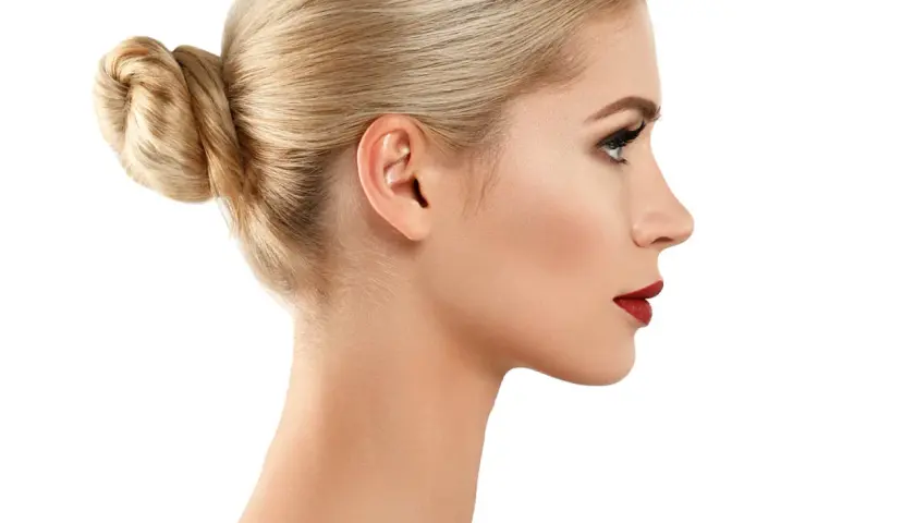 Profil kobiety z blond kokiem i subtelnym garbatym nosem, podkreślonym czerwonymi ustami.