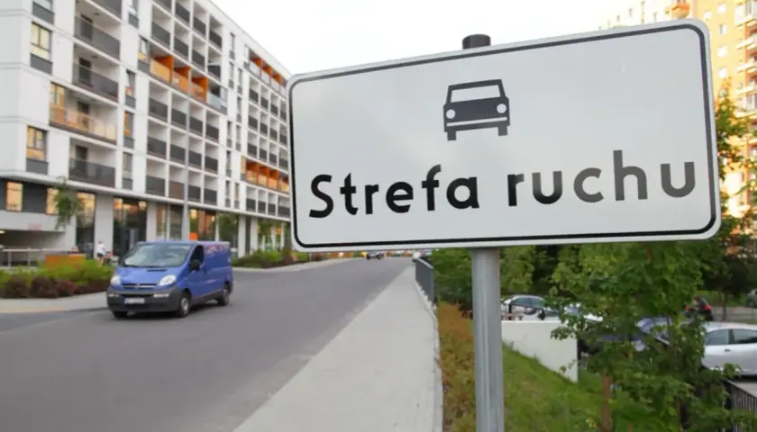 Znak "Strefa ruchu" na drodze wewnętrznej obok nowoczesnego osiedla.