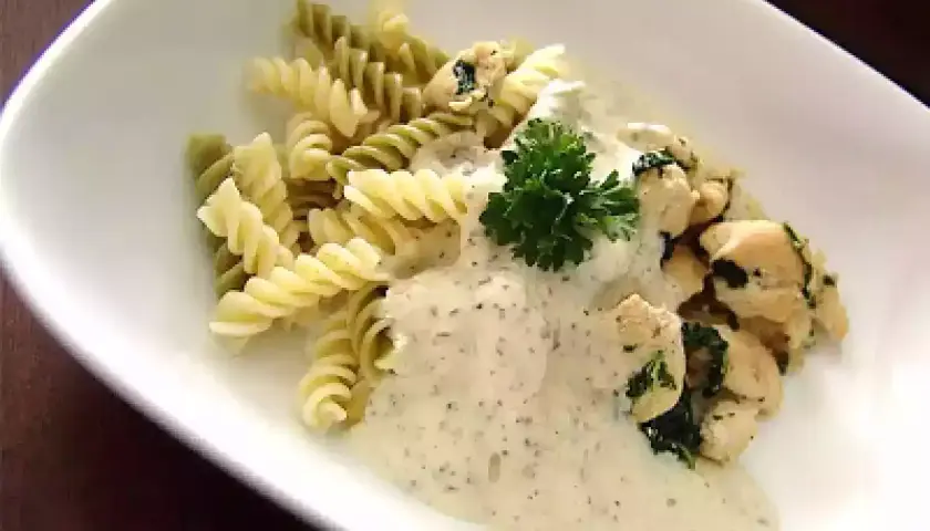 Pâtes fusilli, poulet et sauce crémeuse, garnies de persil. Un délice de pâtes pesto mozzarella.