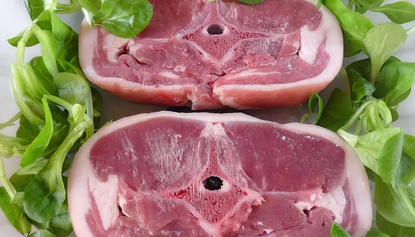 Dwa soczyste kotlety jagnięce otoczone świeżą sałatą. Zastanawiasz się, ile kosztuje kilogram jagnięciny?