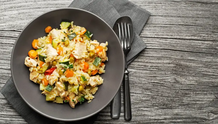 Piatto di riso con pollo e verdure miste, un esempio di alimentazione funzionale per un pasto completo e nutriente.