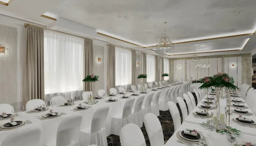 Elegancka, biała sala weselna z długimi stołami nakrytymi białymi obrusami i białymi pokrowcami na krzesłach.