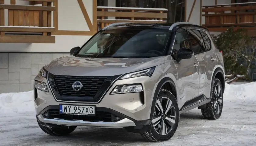 Zastanawiasz się, jaki silnik wybrać do Nissana X-Trail? Ten nowoczesny SUV w kolorze szampańskim prezentuje się świetnie na tle zimowego krajobrazu.