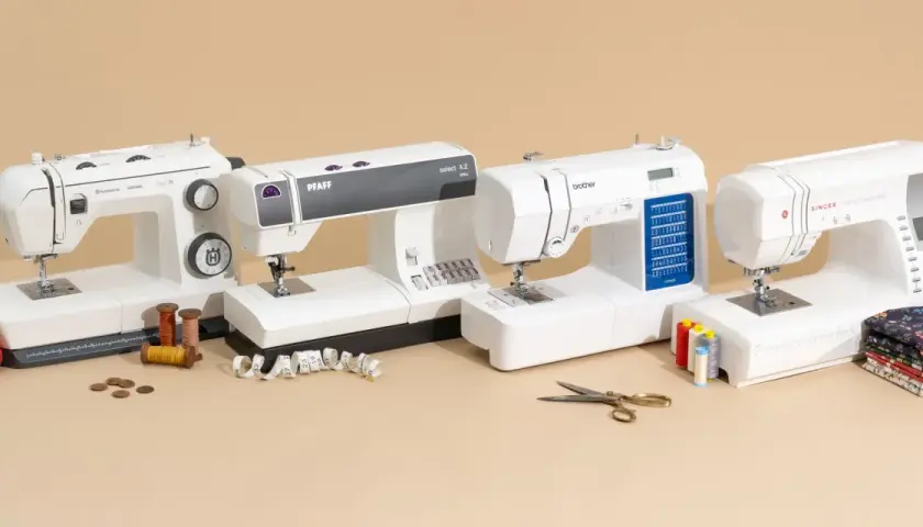 Four sewing machines are lined up, ready for beginners to learn how to use a sewing machine. Spools of thread, scissors, and fabric are nearby.