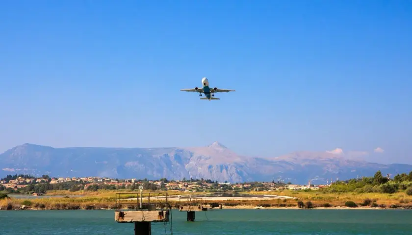 Airplane ascending over a coastal town near the Sicily airport, with mountains in the background.