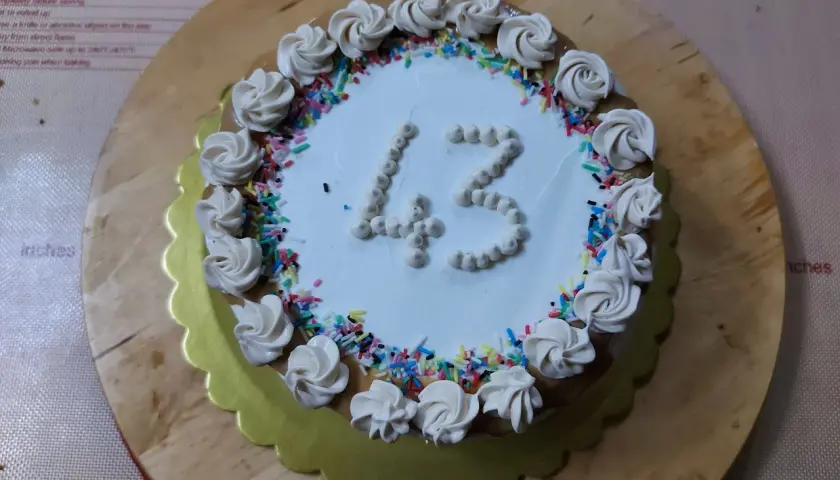 Torta di compleanno particolare con decorazioni a rosa e codette colorate, numero 43 in crema.