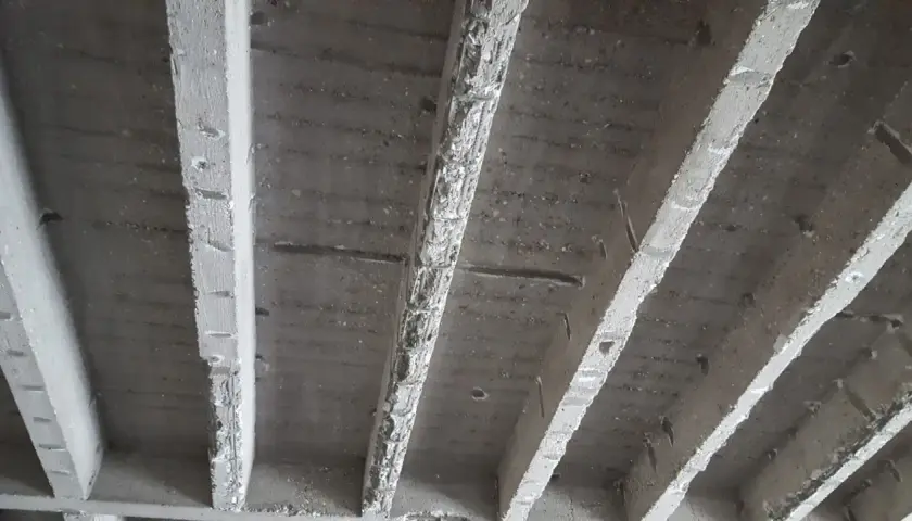 Unterseite einer stahlbeton rippendecke mit sichtbaren Rippen und Bewehrung.