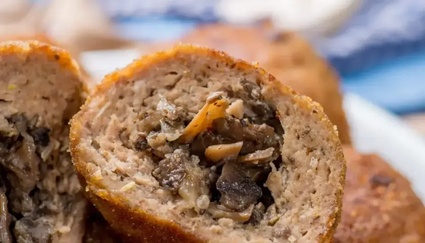 Kotlety mielone z pieczarkami, przekrojone na pół, ukazujące soczyste, aromatyczne wnętrze.
