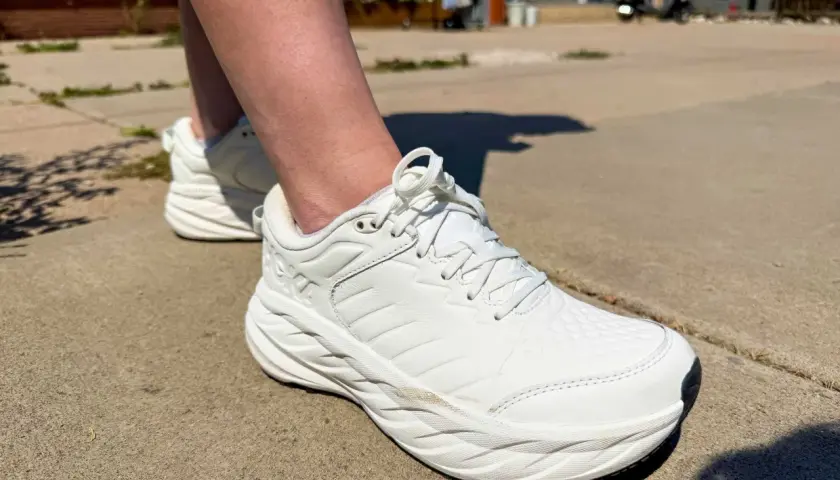 White walking shoes on a sidewalk. The question of whether walking shoes should be a size bigger is on many minds.