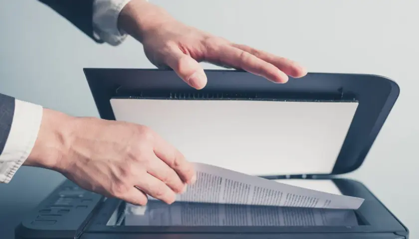 Un homme en costume utilise un scanner ged pour numériser un document important.