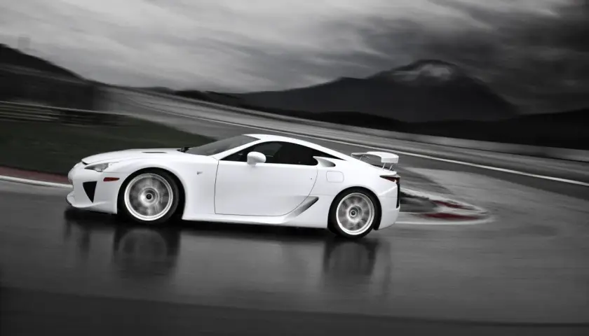 Biały Lexus LFA na torze wyścigowym, z rozmytym tłem gór i nieba.