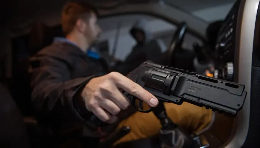 Mężczyzna w samochodzie trzyma pistolet na kule gumowe. Czy pistolet na kule gumowe jest legalny? To pytanie nurtuje wielu.