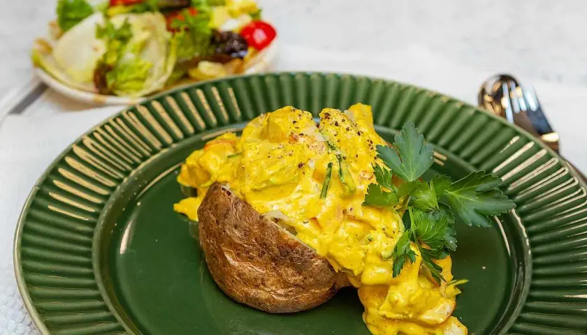 En saftig bakad potatis med en krämig kycklingfyllning, toppad med färsk persilja. Serveras med en fräsch sallad.