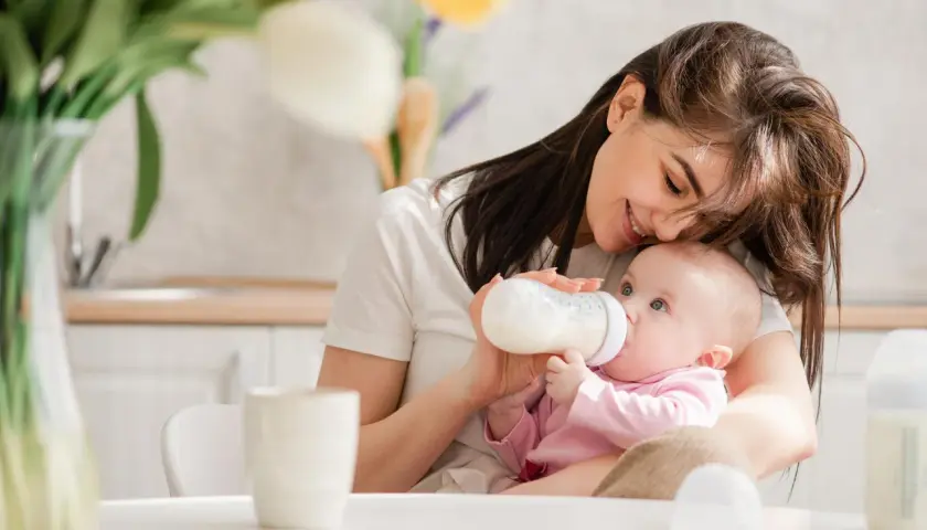 Mama karmi niemowlaka z butelki. Uważaj na przekarmienie niemowlaka mlekiem modyfikowanym objawy, by uniknąć problemów.