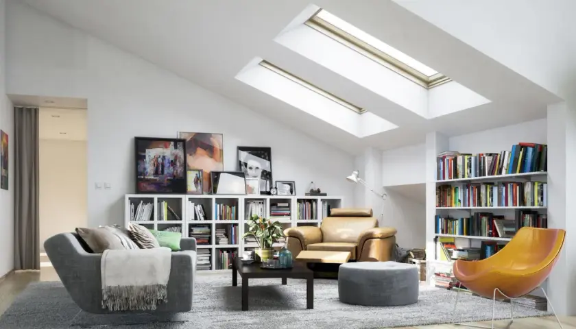 Gemütliche dachgeschosswohnung einrichten mit bequemen Sesseln, Bücherregalen und viel Licht durch Dachfenster.