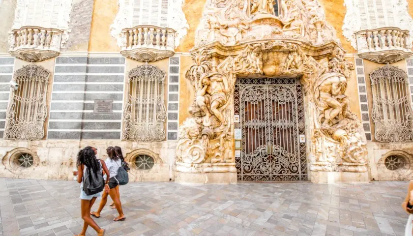 Dos chicas pasean frente a un edificio ornamentado, buscando museos gratis en Valencia.