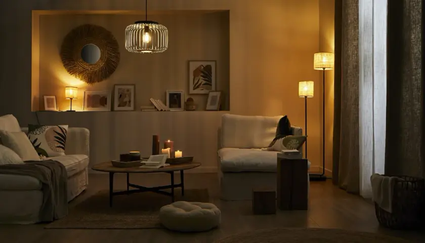 Przytulny salon z dwiema lampami, które tworzą ciepłą atmosferę. Na stoliku kawowym palą się świece.