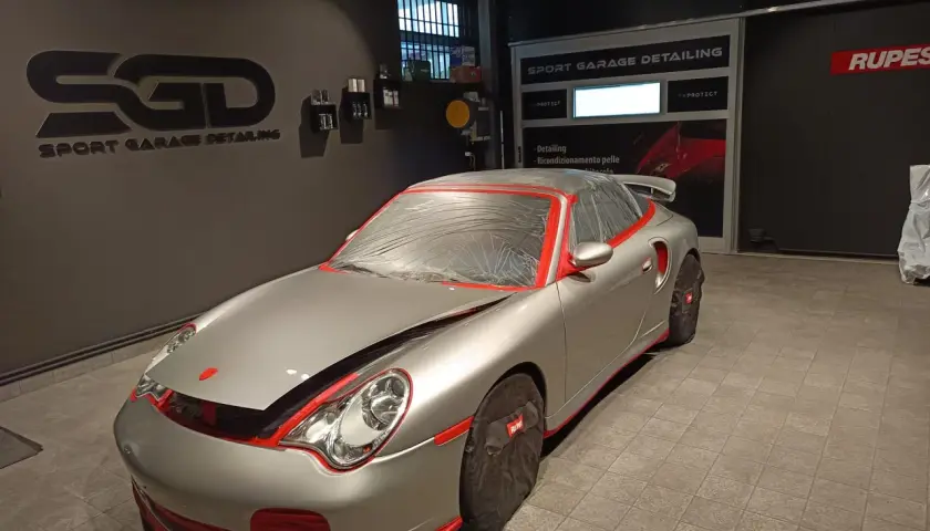 Auto sportiva argentata, mascherata per la preparazione. Inizia il processo per come lucidare auto in questo centro di detailing.