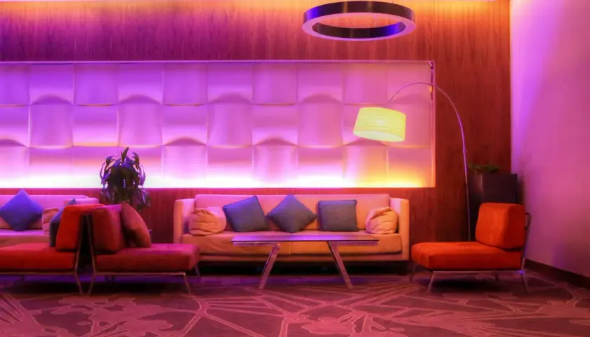 Nowoczesny hotel butikowy co to? Wnętrze z sofami, fotelami i designerską lampą w fioletowym świetle.