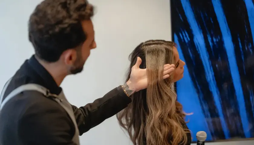 Hombre revisa el pelo elastico de una mujer, mostrando su textura y brillo.