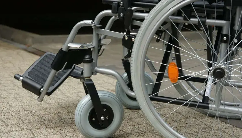 Zbliżenie na wózek inwalidzki z widocznymi kołami i podnóżkiem.