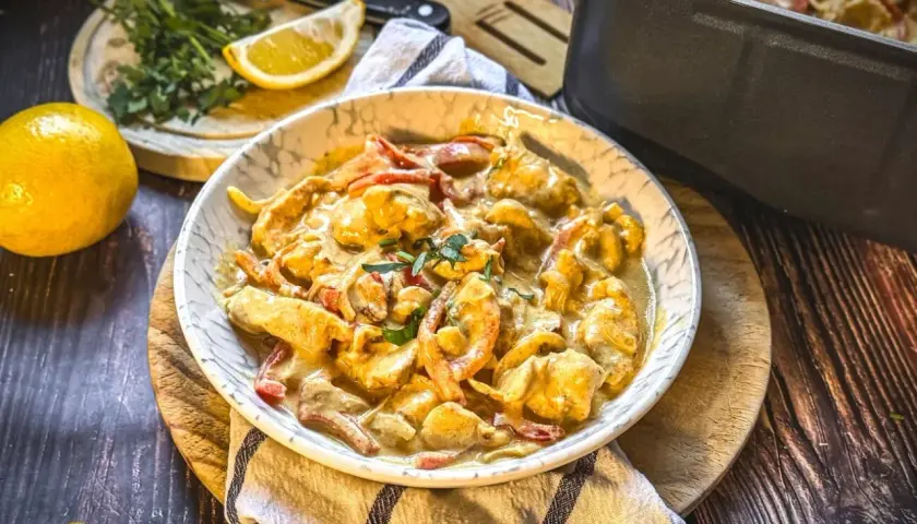 Cremiges Hähnchengeschnetzeltes mit Paprika in einer Schüssel, garniert mit Kräutern. Ein leckeres geschnetzeltes Rezept für jeden Tag.