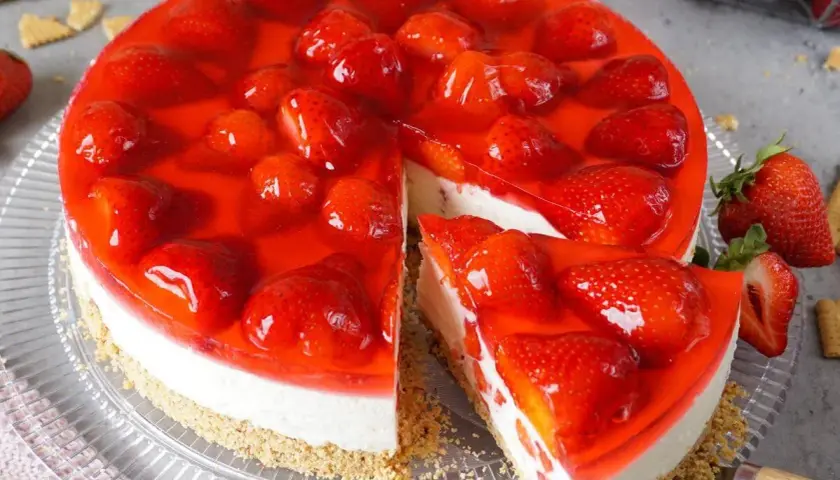Ein köstlicher Erdbeerkuchen ohne Backen, mit frischen Erdbeeren und rotem Tortenguss auf cremigem Boden.