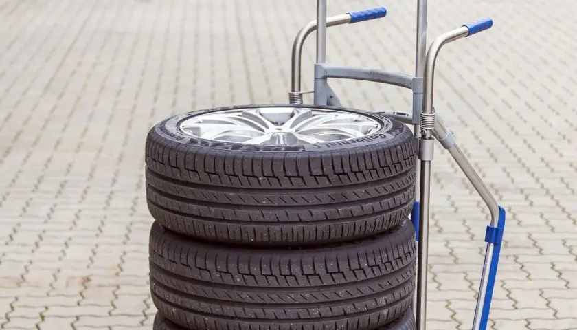 Stos czterech opon samochodowych na wózku. Zastanawiasz się, ile wazy opona? Ta wygląda na solidną!