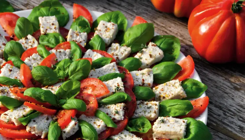 Frischer Tomaten-Mozzarella-Salat mit Basilikum, perfekt für ein veganes Party-Buffet.