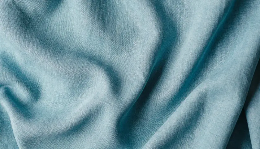 Plissé de textiles artificiels bleu pâle, évoquant la douceur et la fluidité d'une étoffe moderne.