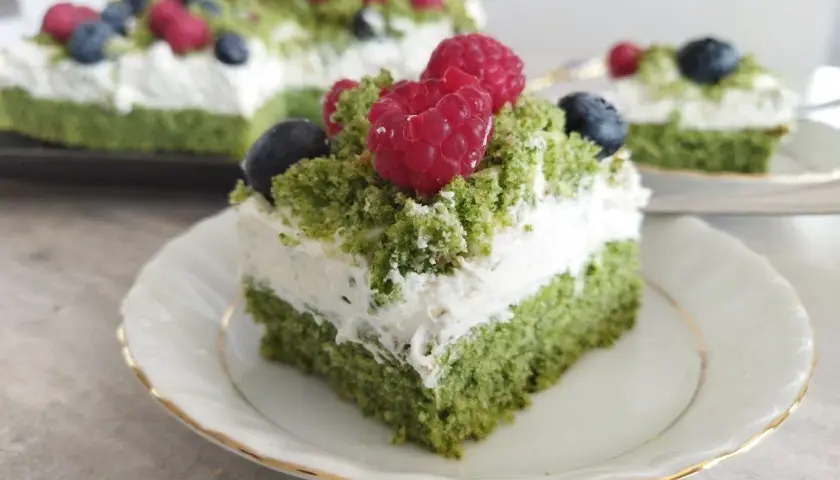 Zielony, puszysty **ciasto leśny mech na dużą blachę z serkiem mascarpone**, ozdobione malinami i borówkami.