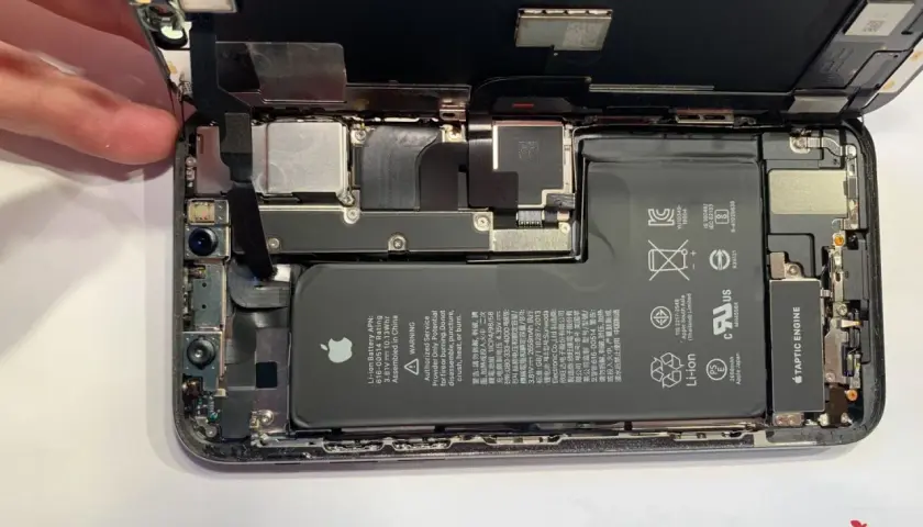 Rozłożony iPhone, gotowy do usuwania wody. Widać baterię, aparat i inne komponenty.